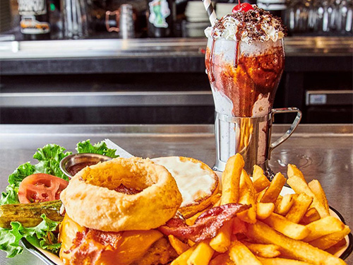 Bacon Cheeseburger with fries next to one of our Alphabet City milkshakes.