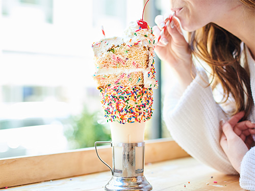 Woman enjoying a Cakeshake®, one of our Bryant Park, New York City milkshakes.