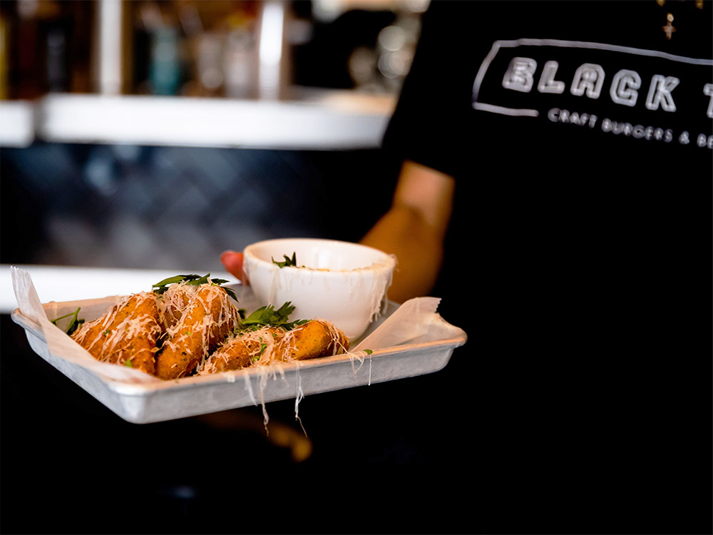 Black Tap employee holding a plate of fried mozzarella at our Grand Central, New York City party place.