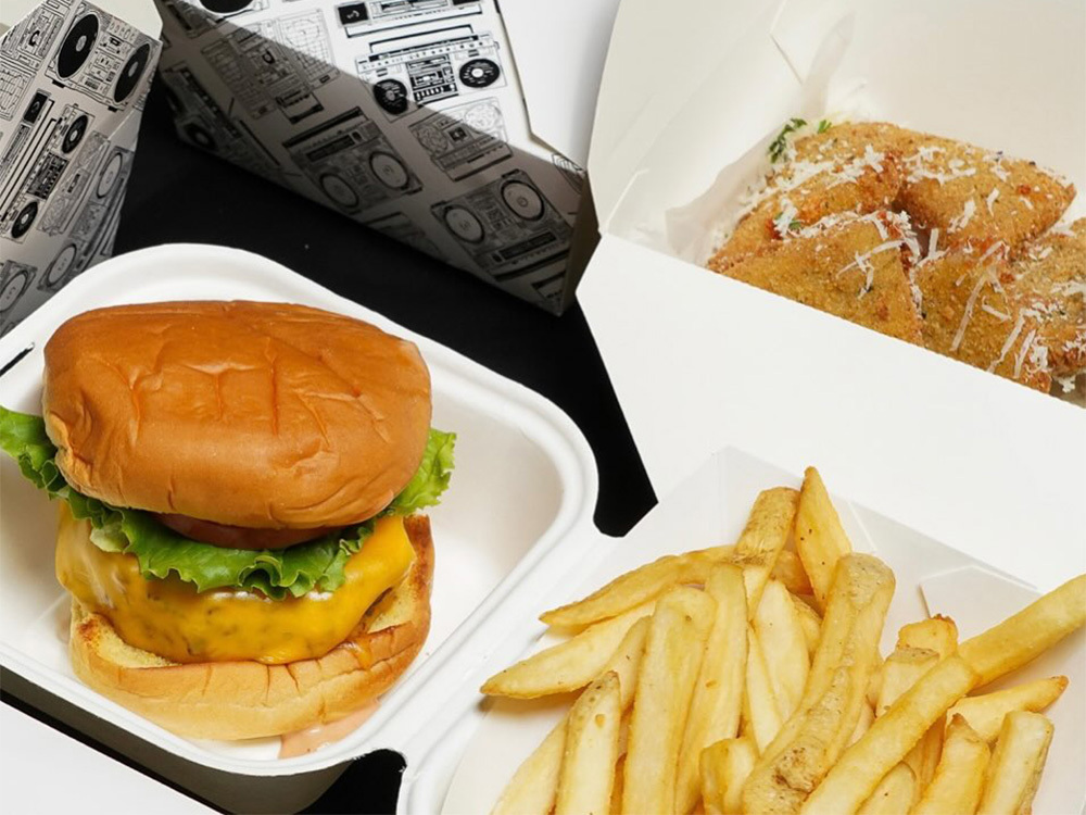 An All-American Burger and French Fries in a to-go container for burger delivery near Bryant Park, New York City.