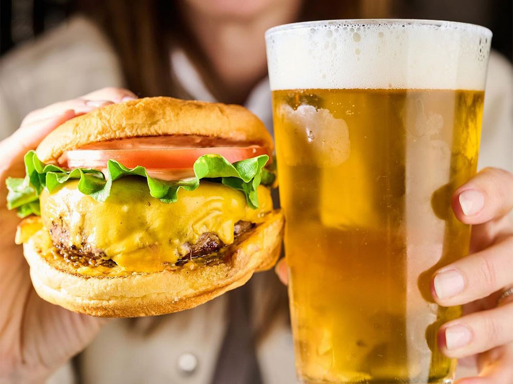 A close view of our All-American Burger and a beer at our Bowery burger place.