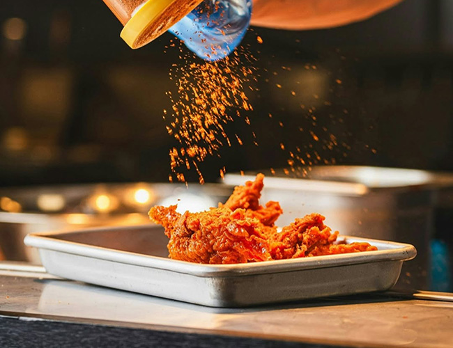 A chef preparing hot wings near Leyton, London, UK.