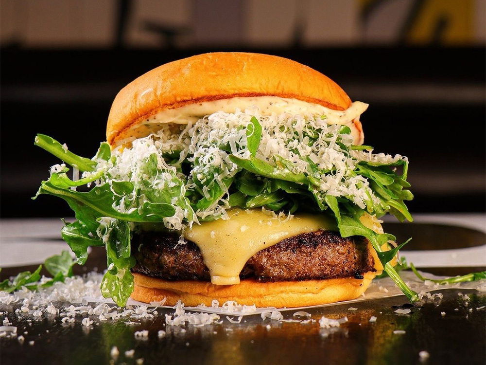 Close up view of hands holding the Wagyu Steakhouse Burger, a top Maryland, London wagyu burger.