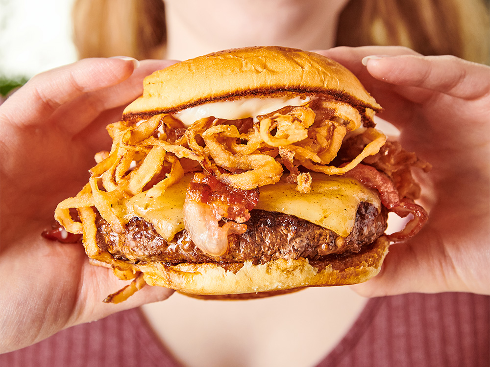 Close up view of hands holding The Champ, one of our gourmet craft wagyu burgers near Maryland, London, United Kingdom.