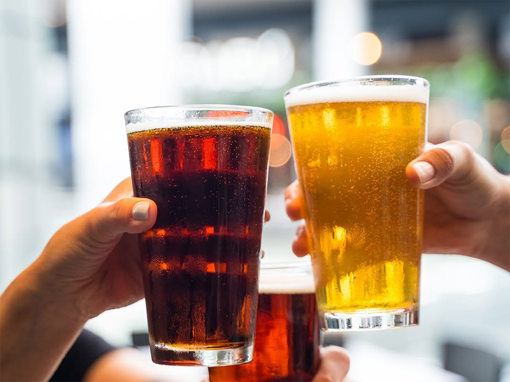 Hands of patrons enjoying drinks at Hudson Yards, Manhattan Happy Hour restaurant.